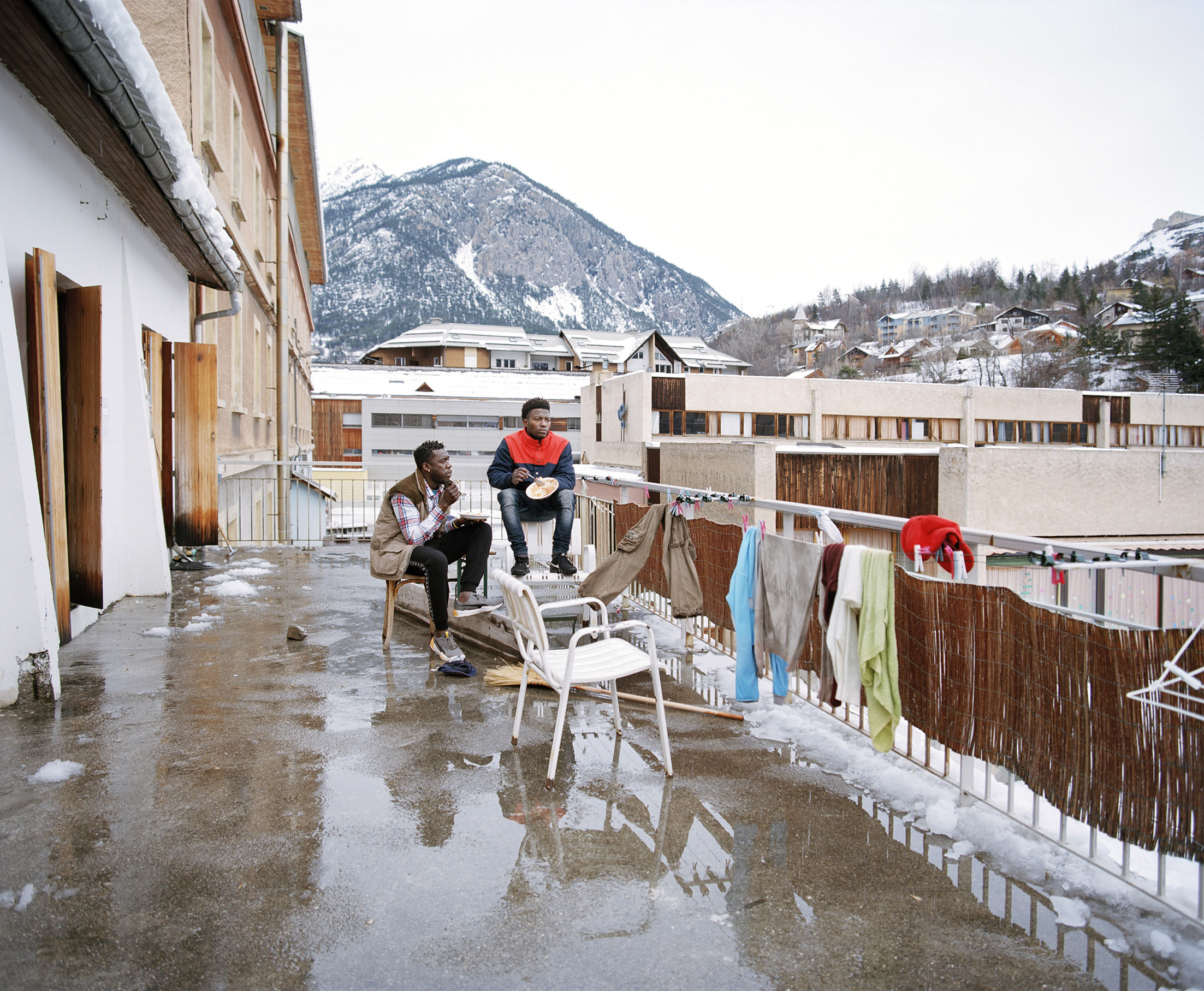 Photographie "Bouba & Ibrahim sur la terrasse du refuge solidaire, Briançon" d'Elisa Larvego, vue de l'exposition "En tous lieux" à la Ferme de la Chapelle