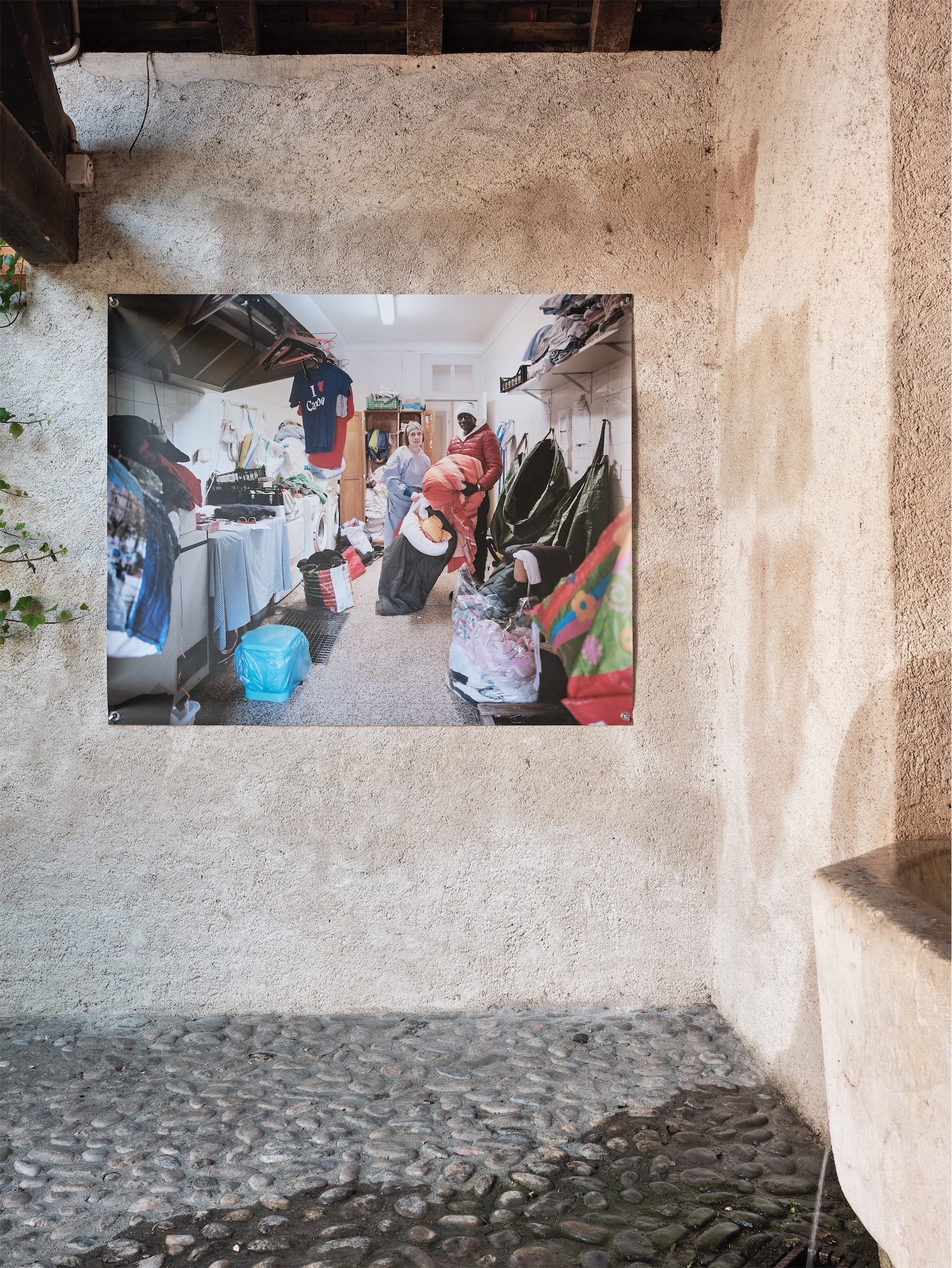 Photographie d'Elisa Larvego, Solange et Alieu dans la lingerie du refuge solidaire, Briançon, vue de l'exposition "En tous lieux" à la Ferme de la Chapelle.