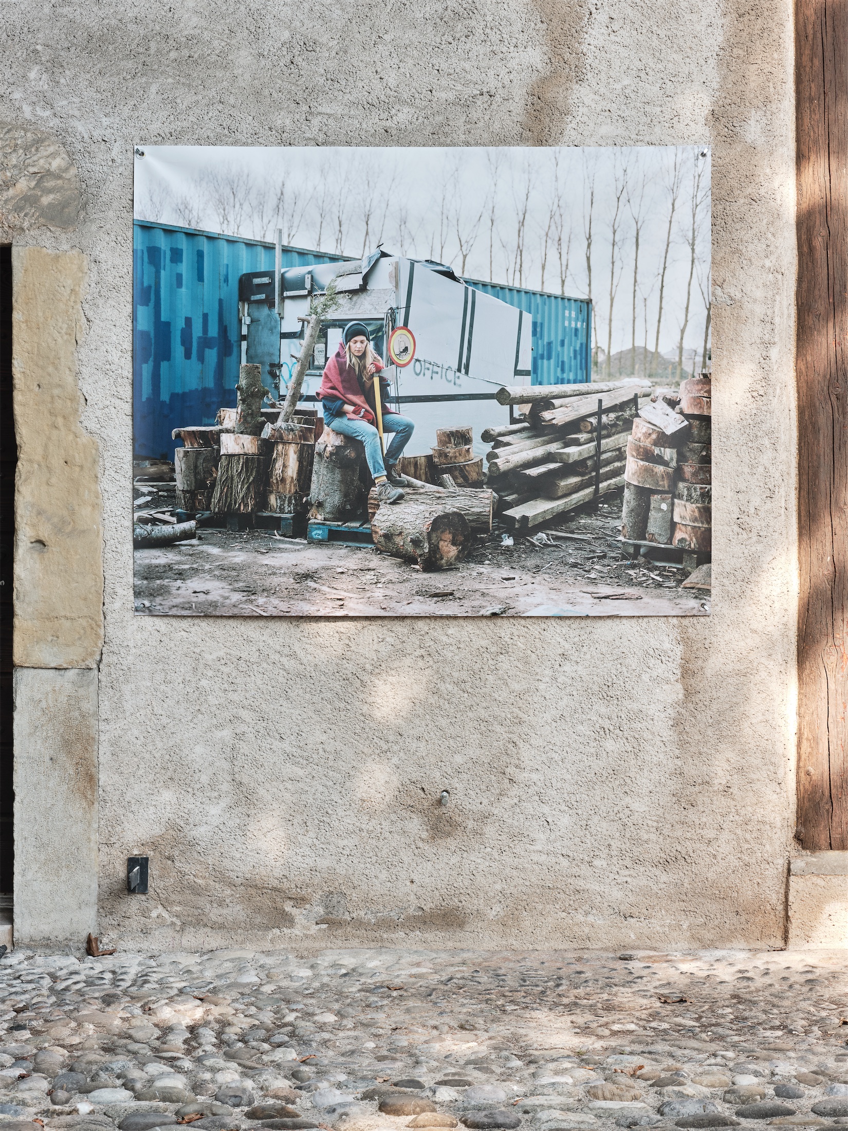 Photo "Koah, entrepôt extérieur du woodyard, Calais" d'Elisa Larvego, vue de l'exposition "En tous lieux" à la Ferme de la Chapelle